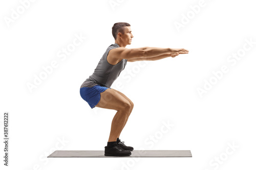 Fit muscular young man doing squat exercises