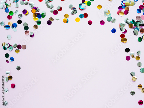 Multi-colored shiny round confetti on a pink background  top view  copy space  flat lay