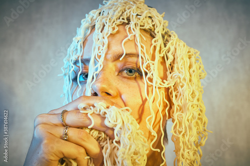Funny hungry girl with curly noodles on her head. photo