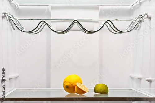 white fridge almost empty with a lime and lemon and a half.