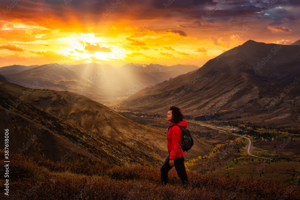 Scenic View of Girl Hiking on a Cloudy Fall Season in Canadian Nature. Dramatic Sunrise Artistic Render. Taken in Tombstone Territorial Park, Yukon, Canada.