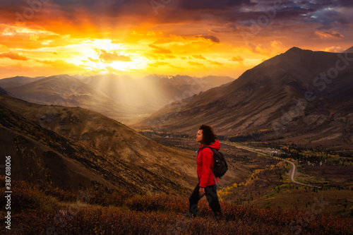 Scenic View of Girl Hiking on a Cloudy Fall Season in Canadian Nature. Dramatic Sunrise Artistic Render. Taken in Tombstone Territorial Park, Yukon, Canada.