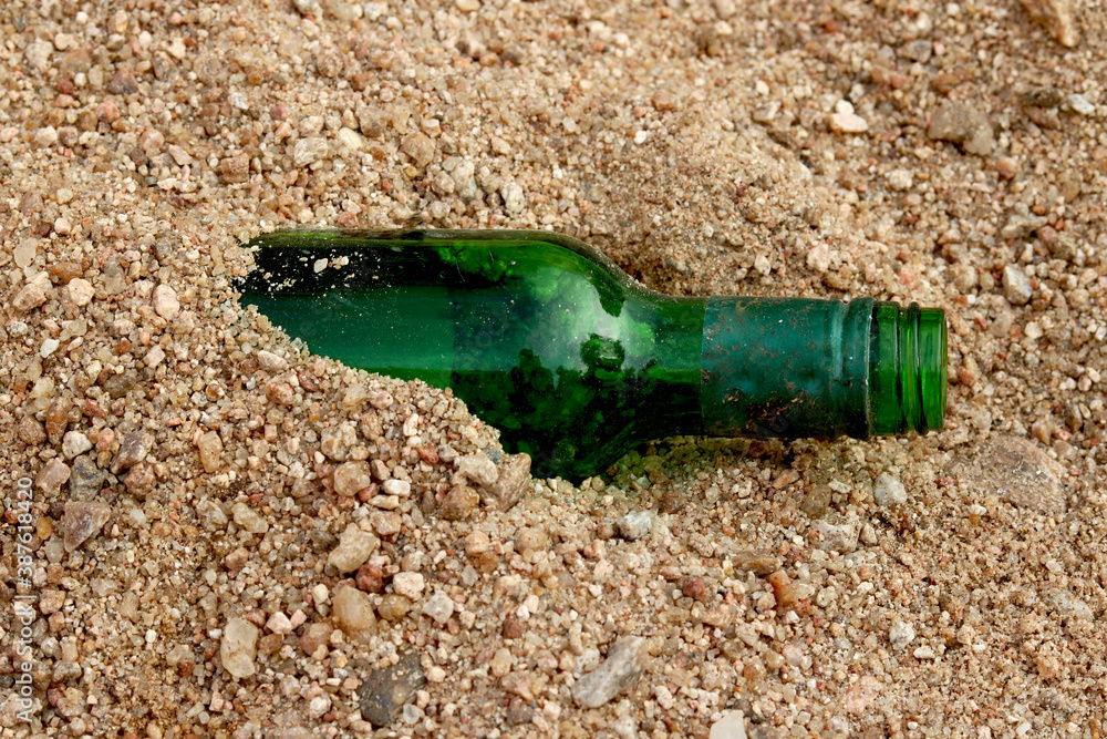 Close-up of green bottles inside sand of a lonely beach Close-up of green bottles inside sand of a lonely beach