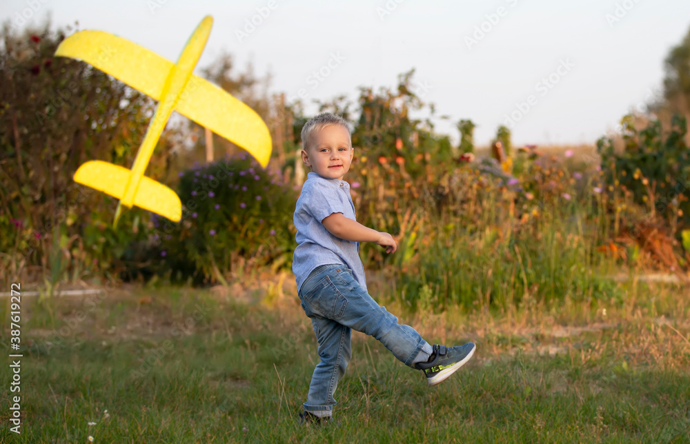 Little boy in the field plays with an airplane.