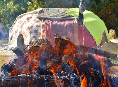 Bonfire with stones and inipi covered with blankets in the background. photo