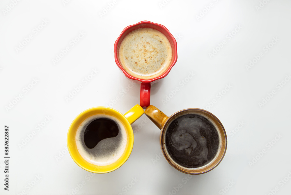 Three cups of coffee in different colors on a white table Three cups of coffee in different colors on a white table