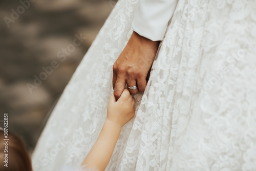 Obraz na płótnie Close-up photo of a bride in luxury wedding dress holding child hand on her wedding day. Wedding concept, ring. Cropped shot. w salonie