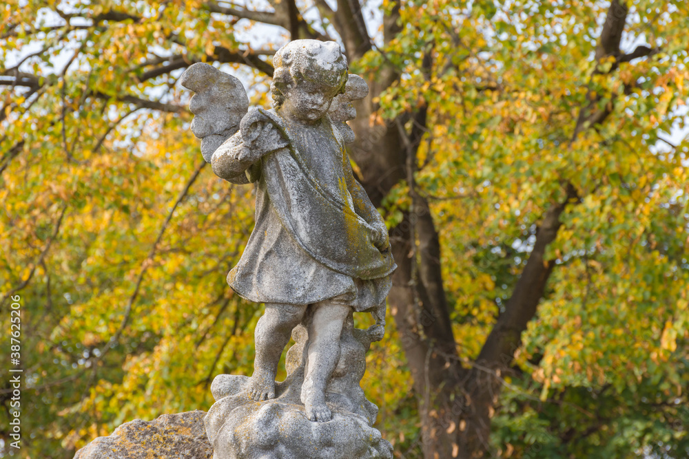 Sculpture of a little angel on a tomb in cemetery. Selective focus