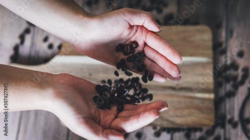 Hands dropping coffee beans on a wooden base