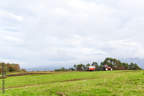 red agricultural tractor standing in a meadow on top of a hill. rural and environment concept