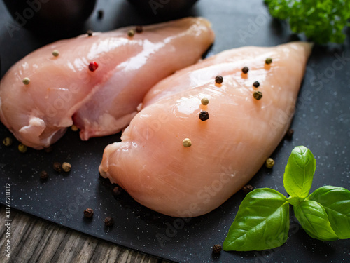 Fresh raw chicken fillet on cutting board with spices on wooden table 