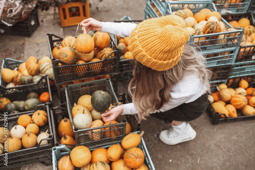 Teenager girl in woolen yellow hat posing at harvest farm and pumpkin patch
