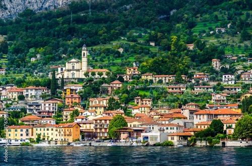 View of village in forest in Lake Como from ferry at sunset, chu