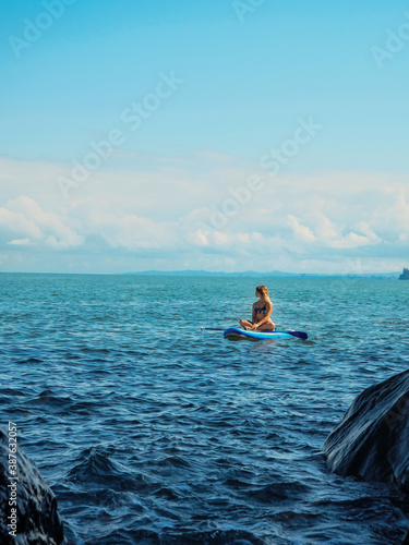 SUP Stand up paddle board. Romantic girl on paddle board in the sea near stone beach. Blue sea Mtsvane Kontskhi Beach, Batumi, Georgia.