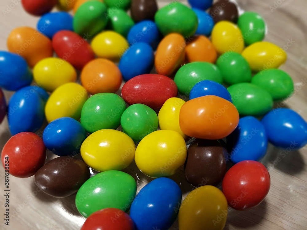 Multicolored chocolate-covered nuts in a transparent plate Multicolored chocolate-covered nuts in a transparent plate
