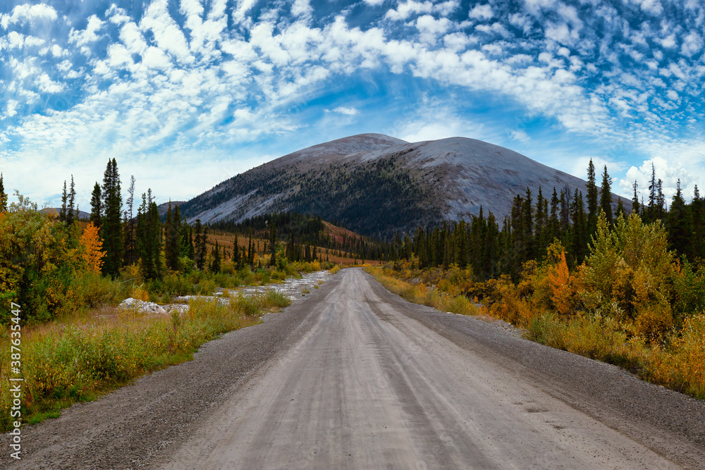 Fototapeta premium View of Scenic Road and Mountains on a Blue Cloudy Sky Fall Day in Canadian Nature. Taken near Tombstone Territorial Park, Yukon, Canada.