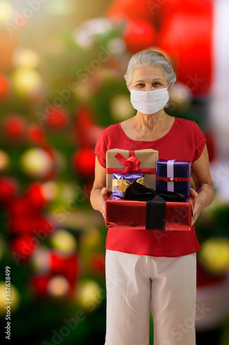 Mature lady with pandemic mask  holding a gift on a chistmas outdoor photo