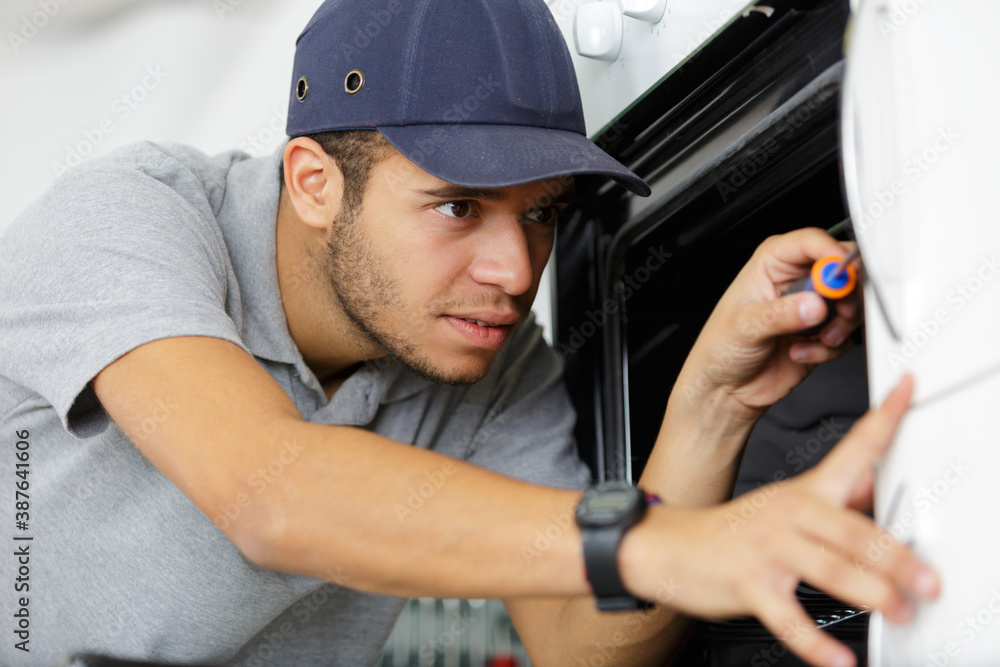 young male technician fixing an oven