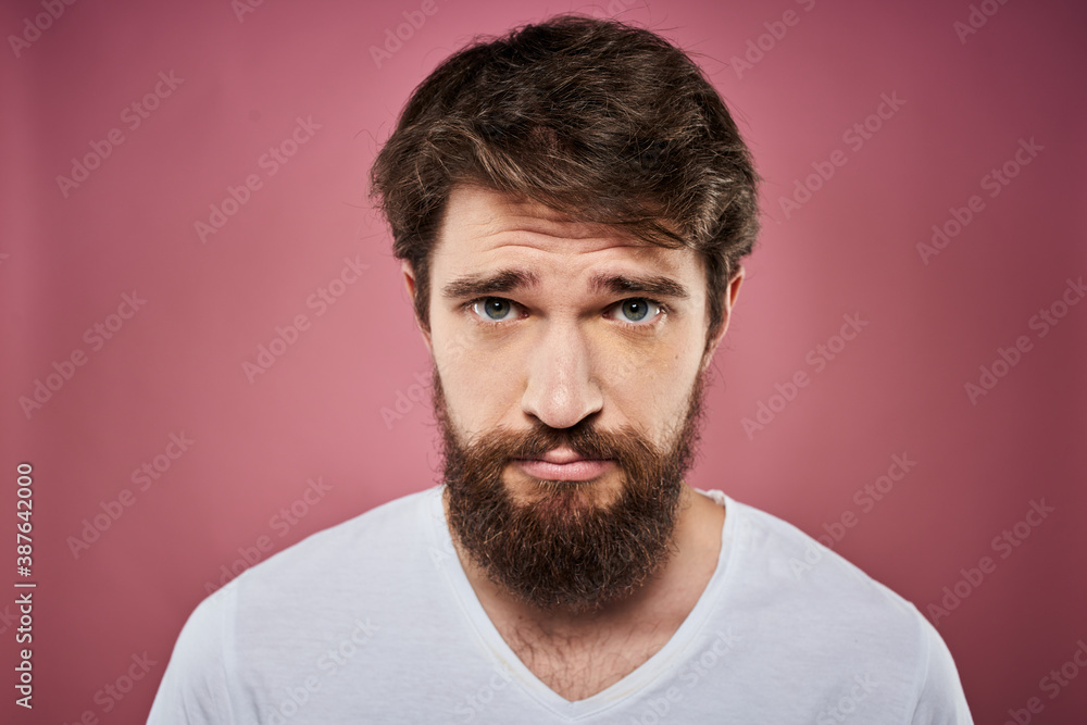 Fototapeta premium Emotional bearded man in white T-shirt discontent pink background