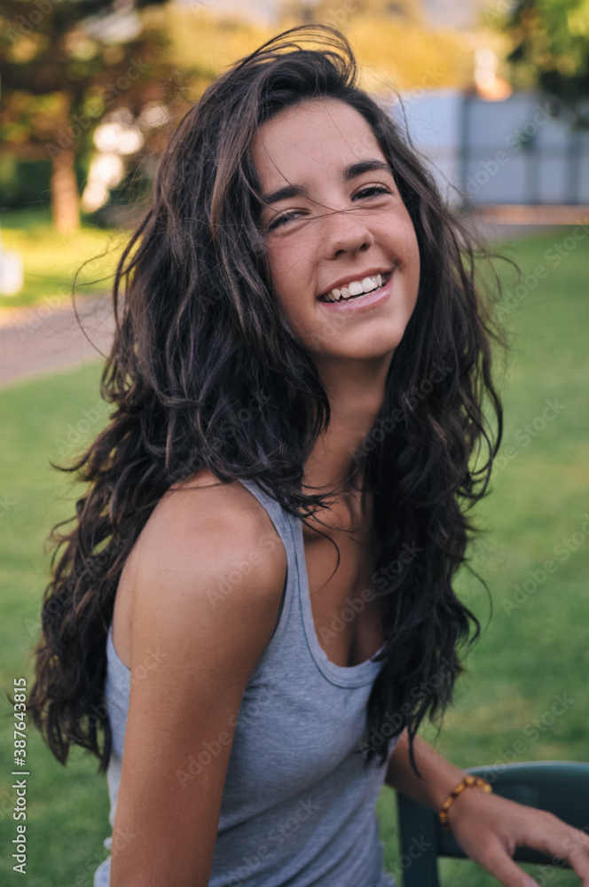 Fototapeta premium Young girl with t-shirt and long hair on a chair in the garden