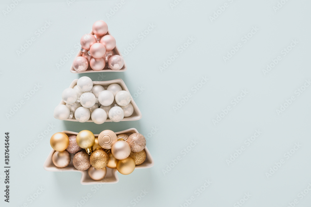 Christmas greeting card pastel shiny baubles in shape of tree on blue. Copy space. Top view. Alternative Xmas tree. Christmas greeting card pastel shiny baubles in shape of tree on blue. Copy space. Top view. Alternative Xmas tree.