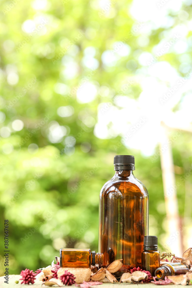 Selection of various sized amber bottles on wooden surface with dried flowers and leaves. Rustic wellness image, portrait orientation 