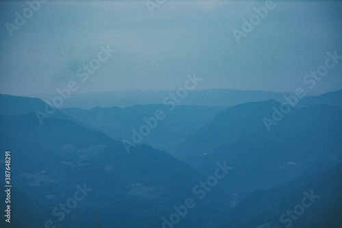 A mountain range shot in the misty, cloudy morning, dark blue silhouettes in Slovenia photo