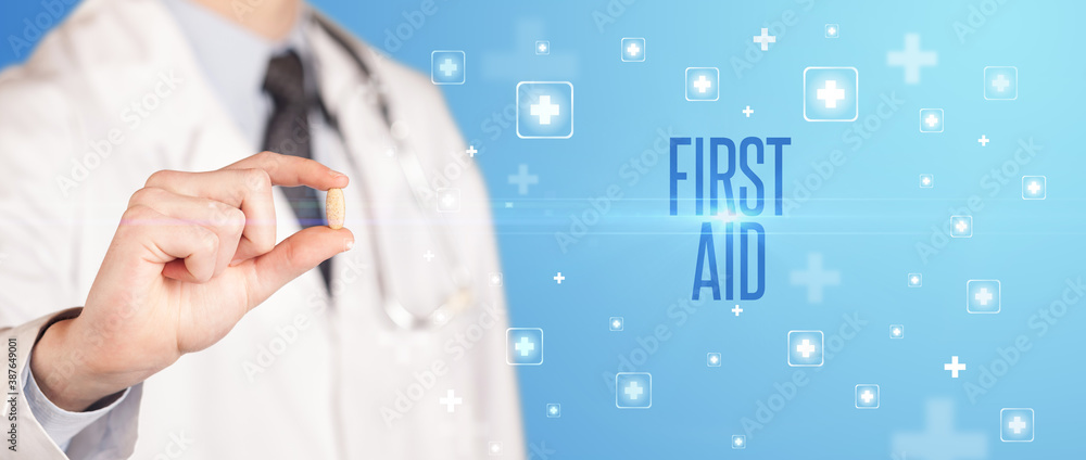 Close-up of a doctor giving a pill with FIRST AID inscription, medical concept Close-up of a doctor giving a pill with FIRST AID inscription, medical concept