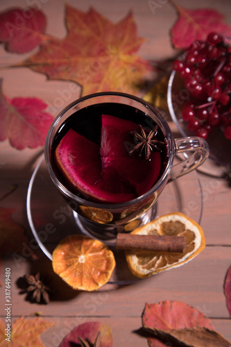 Autumn warming drink mulled wine in a glass Cup on a dark background with autumn leaves. Vertical orientation