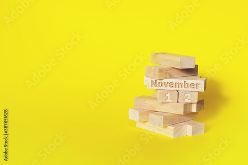 November 12nd. Day 12 of month, Calendar date. Wooden blocks folded into the tower with month and day on yellow background, with copy space. Autumn month, day of the year concept. photo