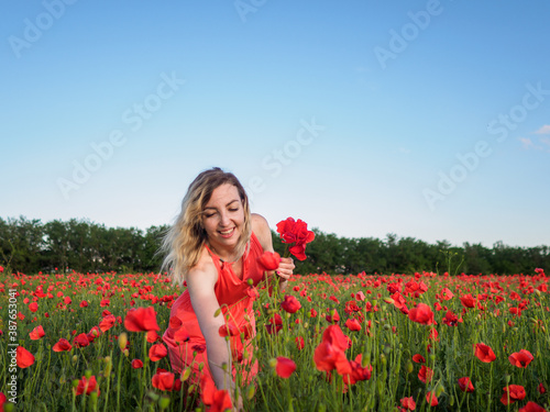 Young girl in a red dress in a poppy field 