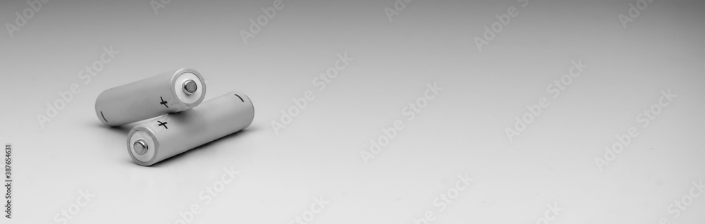 A pair of white batteries or accumulators on a light background. One lies on top of the other. A pair of white batteries or accumulators on a light background. One lies on top of the other.