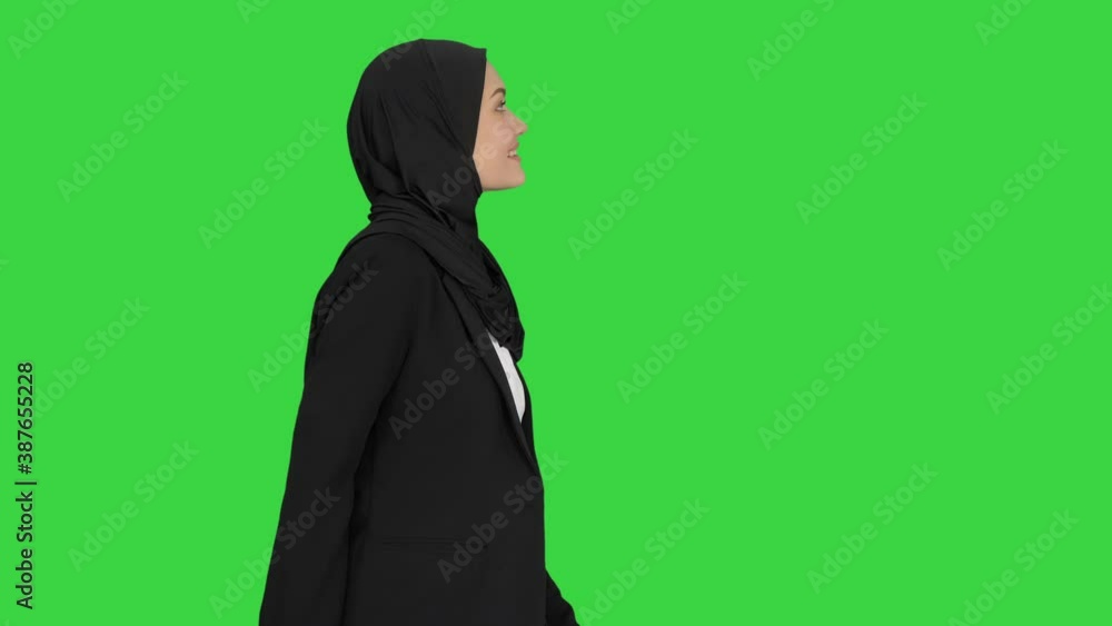 Smiling islamic female model wearing hijab walking and looking ahead on a Green Screen, Chroma Key. Smiling islamic female model wearing hijab walking and looking ahead on a Green Screen, Chroma Key.