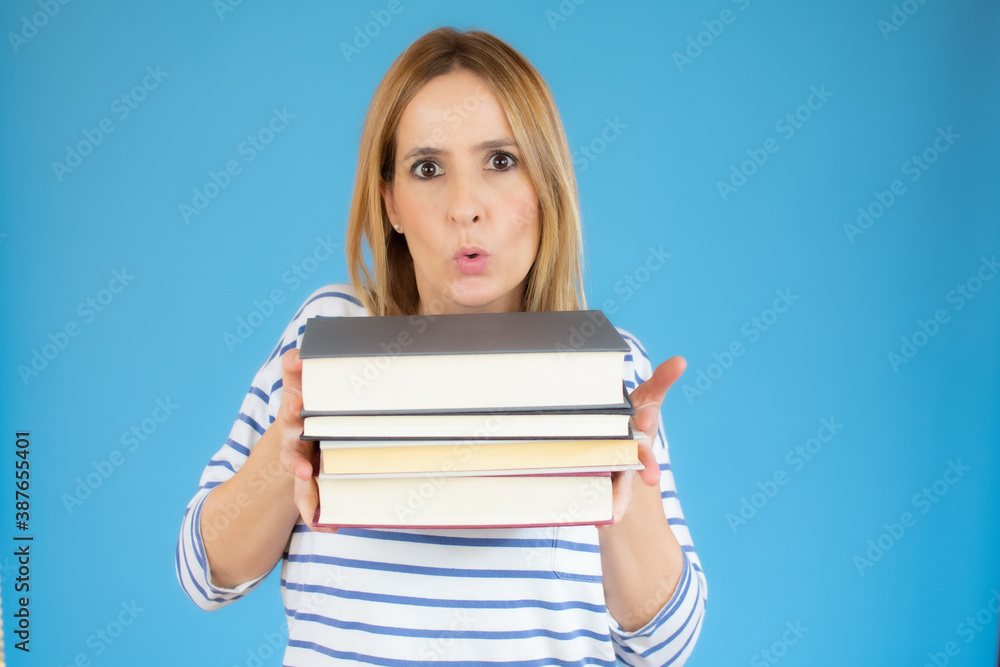 Isolated young happy beautiful woman holding books over blue background. Isolated young happy beautiful woman holding books over blue background.