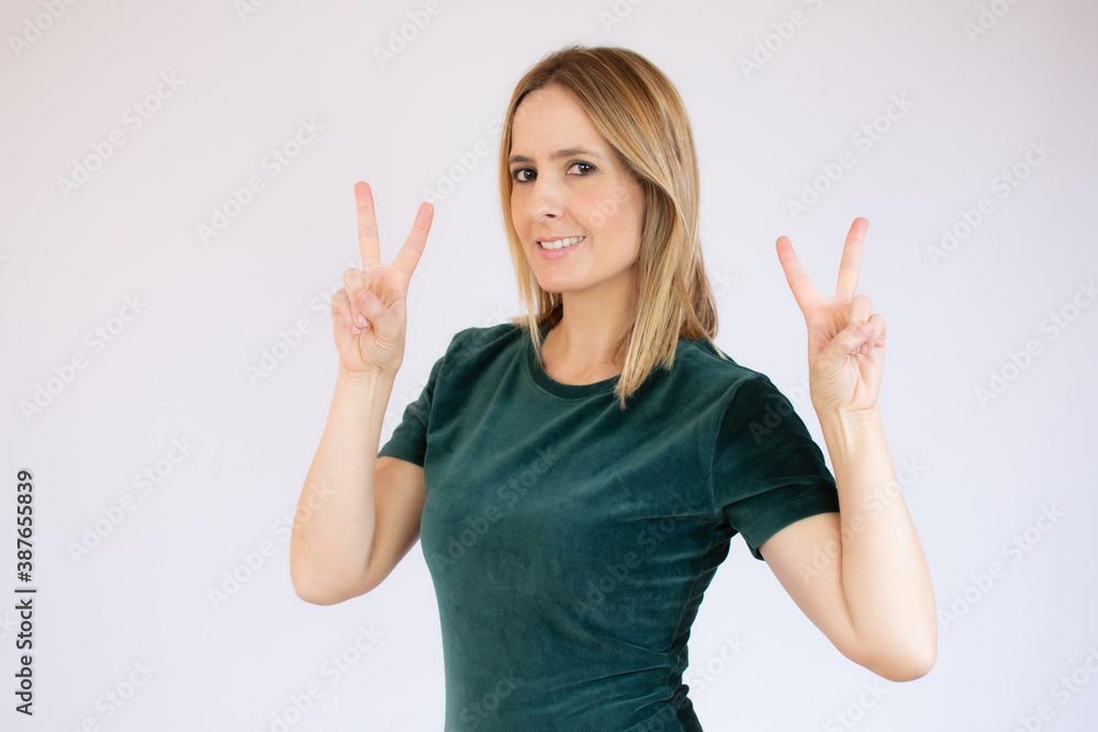 Portrait of a smiling happy woman showing victory sign and looking at camera isolated on the white background Portrait of a smiling happy woman showing victory sign and looking at camera isolated on the white background