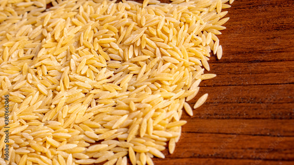 Raw dry uncooked Orza Risoni pasta spaghetti noodle on white bowl wooden background for basil tomato pesto sauce Homemade Italian food organic whole wheat vegan spaghetti for a healthy meal Raw dry uncooked Orza Risoni pasta spaghetti noodle on white bowl wooden background for basil tomato pesto sauce Homemade Italian food organic whole wheat vegan spaghetti for a healthy meal