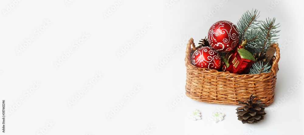 basket with red Christmas balls toys and Christmas tree branches on a white background