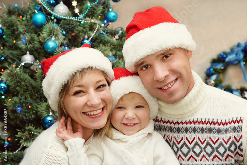 portrait of a young family celebrating Christmas at home near Christmas tree