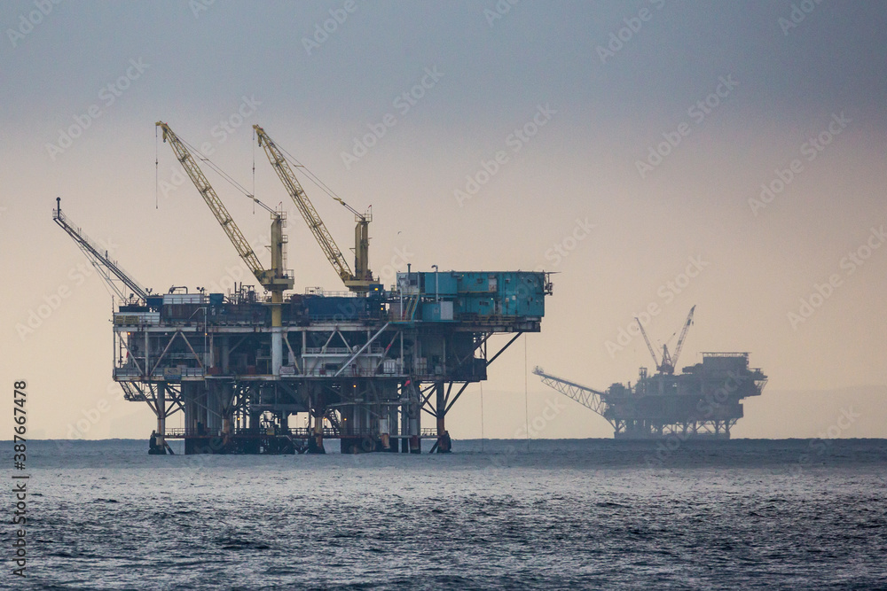 A pair of offshore oil wells off the coast of California during sunrise.