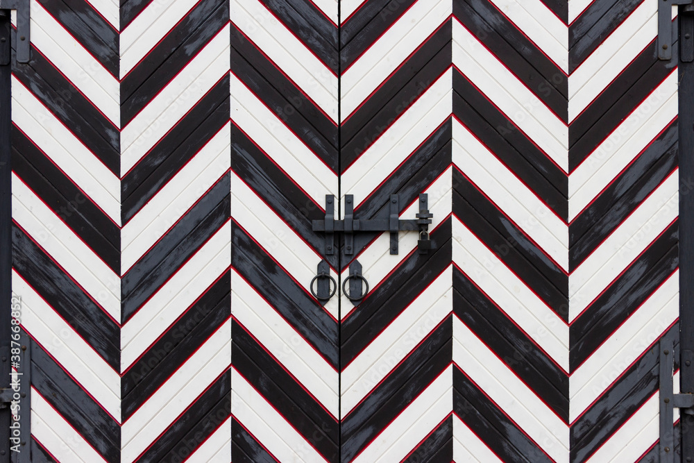 Wrought iron door handles in the form of a ring and a steel bolt closed with a padlock on the gate in a medieval castle.