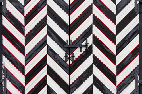 Fotografie Wrought iron door handles in the form of a ring and a steel bolt closed with a padlock on the gate in a medieval castle
