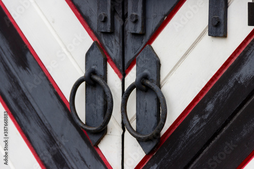 Obraz na plátně Wrought iron door handles in the form of a ring and a steel bolt closed with a padlock on the gate in a medieval castle