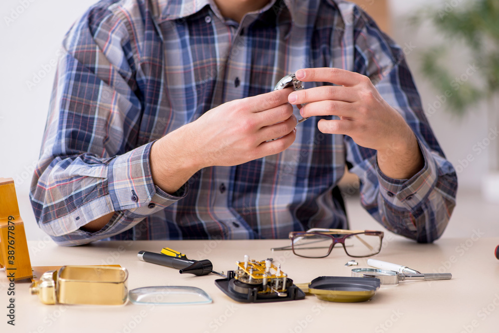 Young male watchmaker working in the workshop