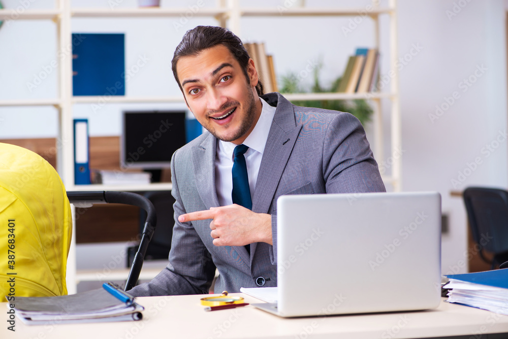 Young male employee looking after newborn at workplace Young male employee looking after newborn at workplace
