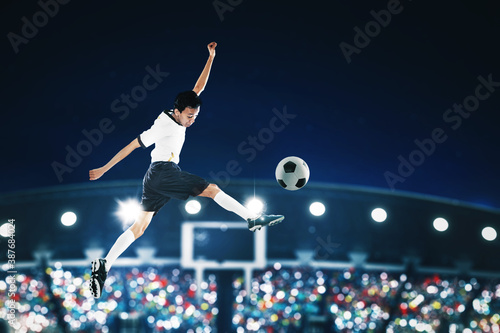 Soccer player kicking ball with powerful on stadium