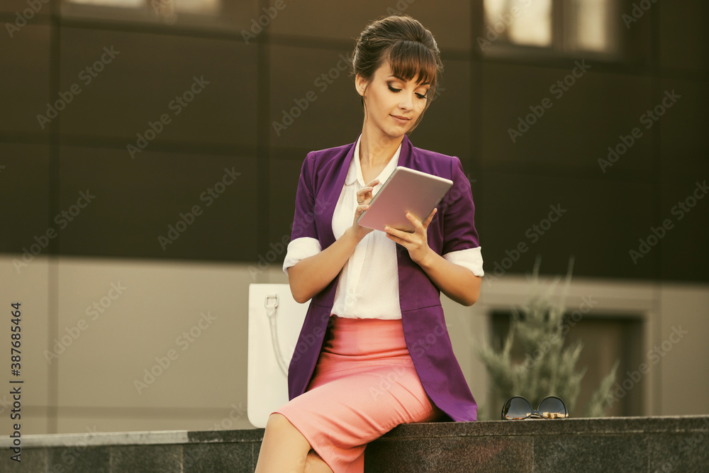 Young fashion business woman in purple blazer and pink pencil skirt using tablet computer Young fashion business woman in purple blazer and pink pencil skirt using tablet computer
