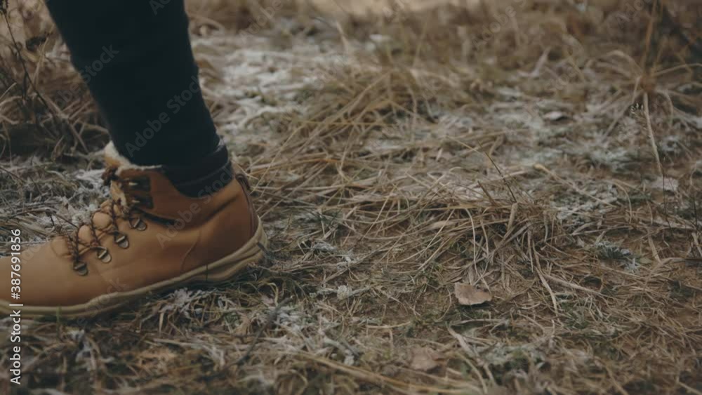 Feet in boots walking on frozen ground. Autumn, hiking, sport concept. Filmed on cinema camera. 12 bit color space. Feet in boots walking on frozen ground. Autumn, hiking, sport concept. Filmed on cinema camera. 12 bit color space.