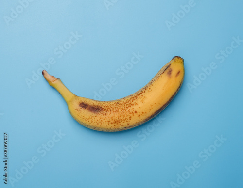 one yellow mellow spotted banana isolated on blue background