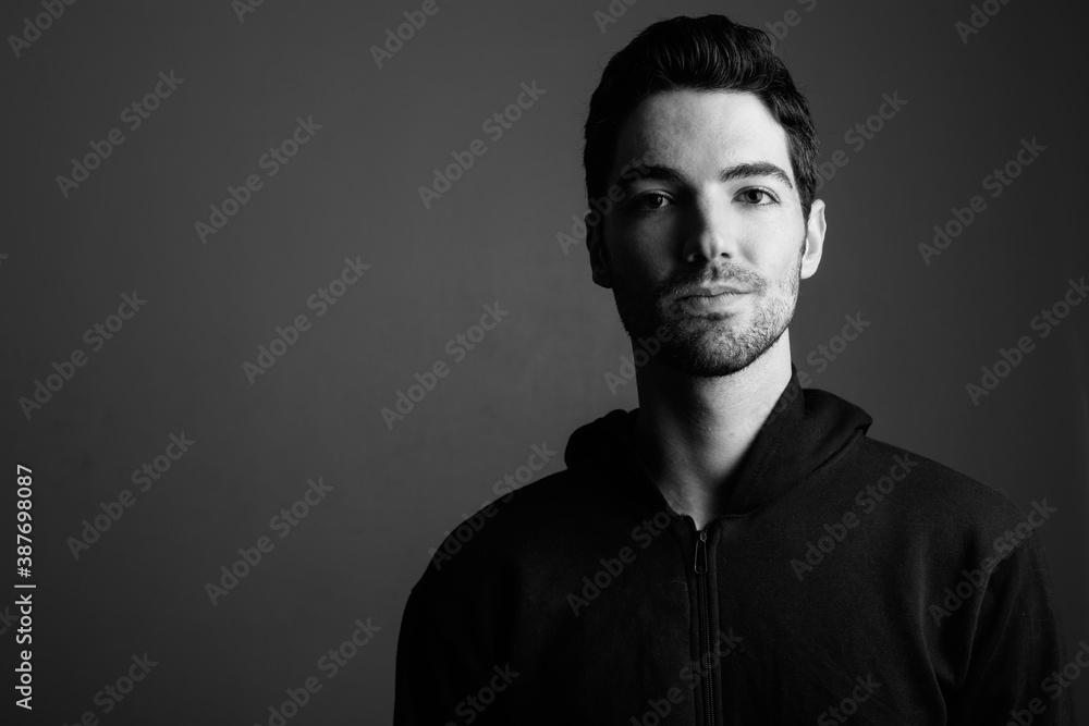 Young handsome man wearing hoodie against gray background