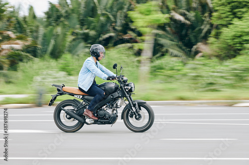 Serious Vietnamese man riding fast on motorcycle  blurred motion in background